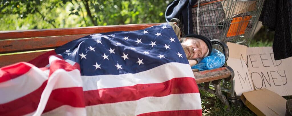 Showing Poverty in America, a homeless man uses our flag as a blanket.